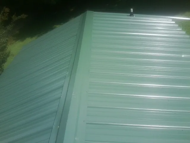 New green metal panels meeting at the ridge of a roof — Flat Roof Repair work by our crew in Chancellor