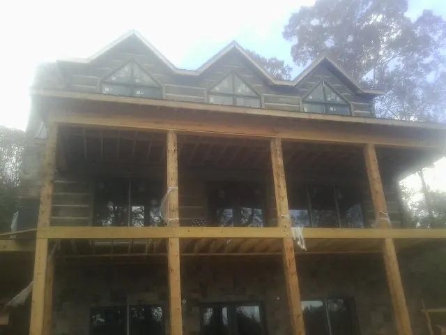 Dormers and porch framing on a large log home under construction — Roof Coating work by our crew in Chancellor