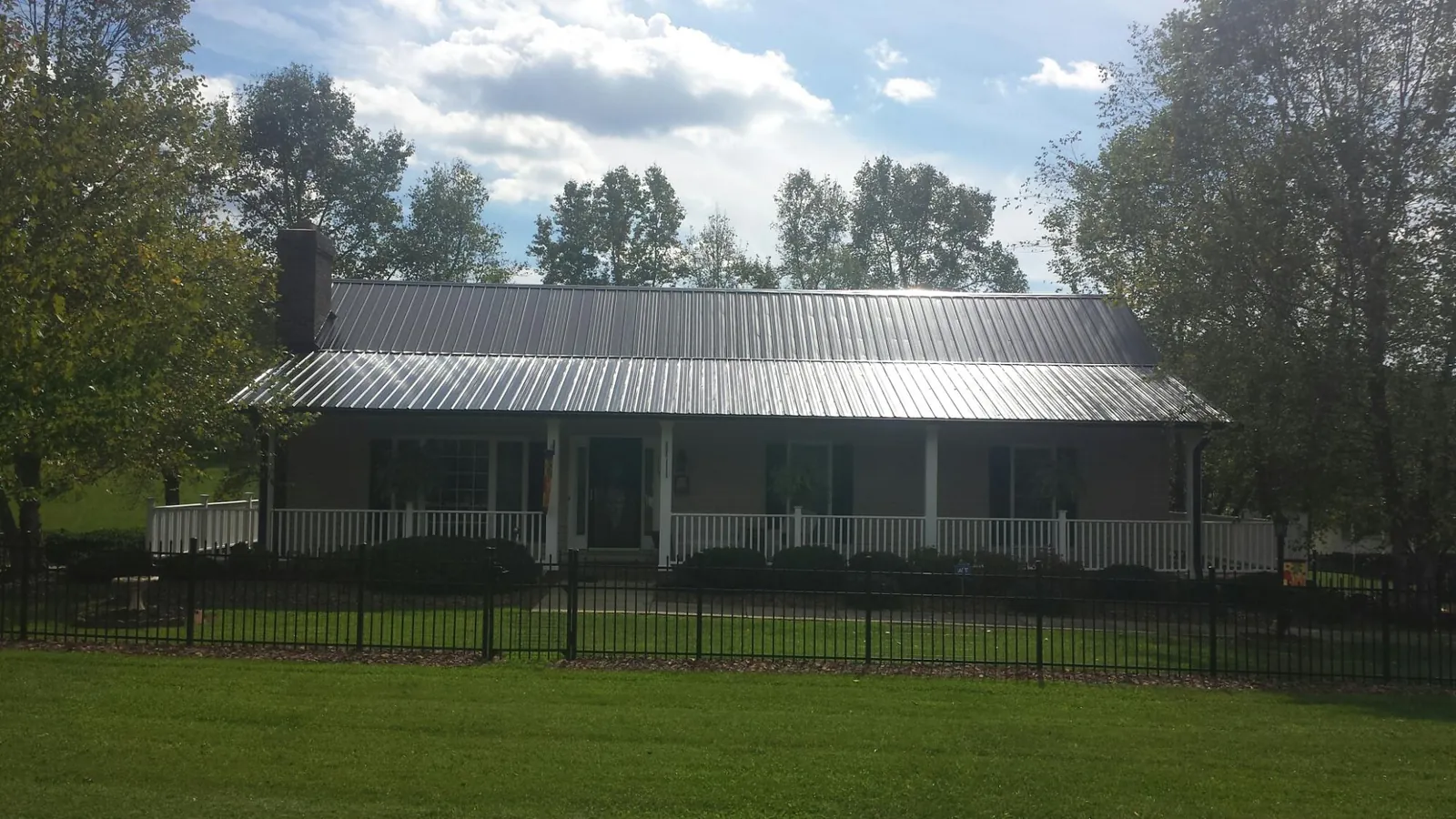 Gray metal roof on a brick ranch with a full width front porch — Gutter Guard Installation work by our crew in Chancellor