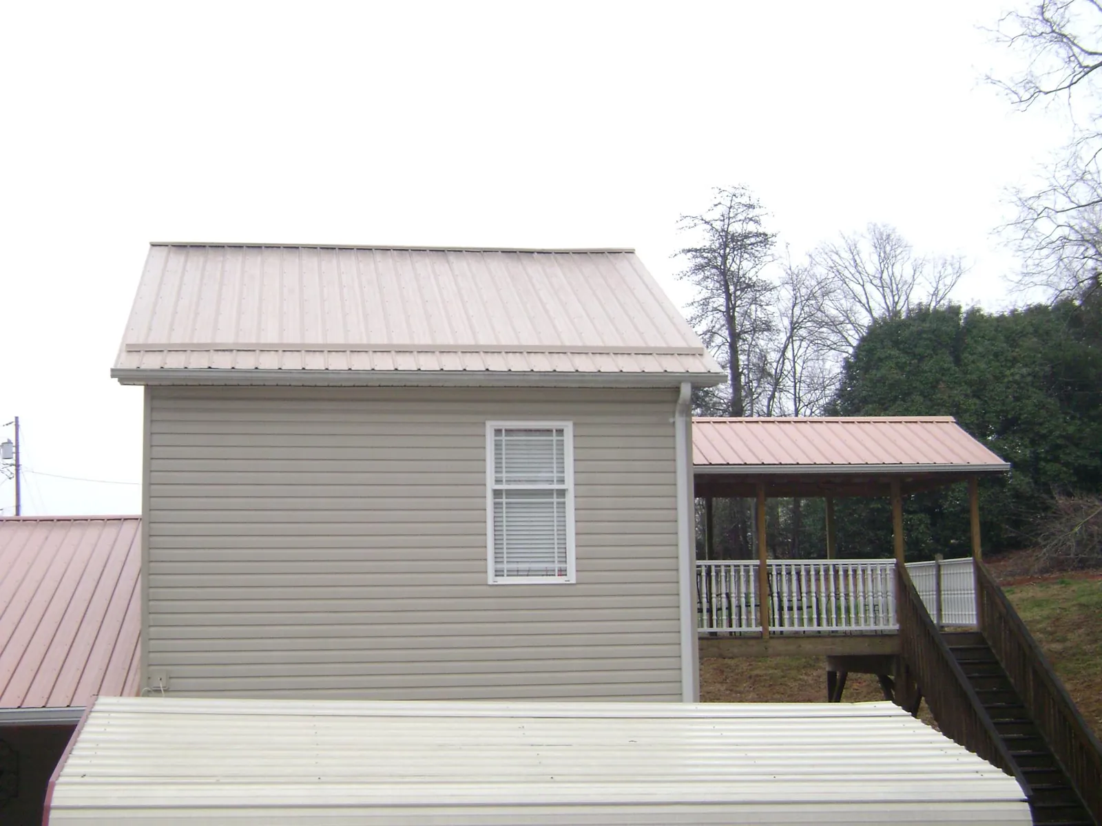 Tan metal roofs on a two story addition and attached porch, from a Roof Replacement job in Chancellor