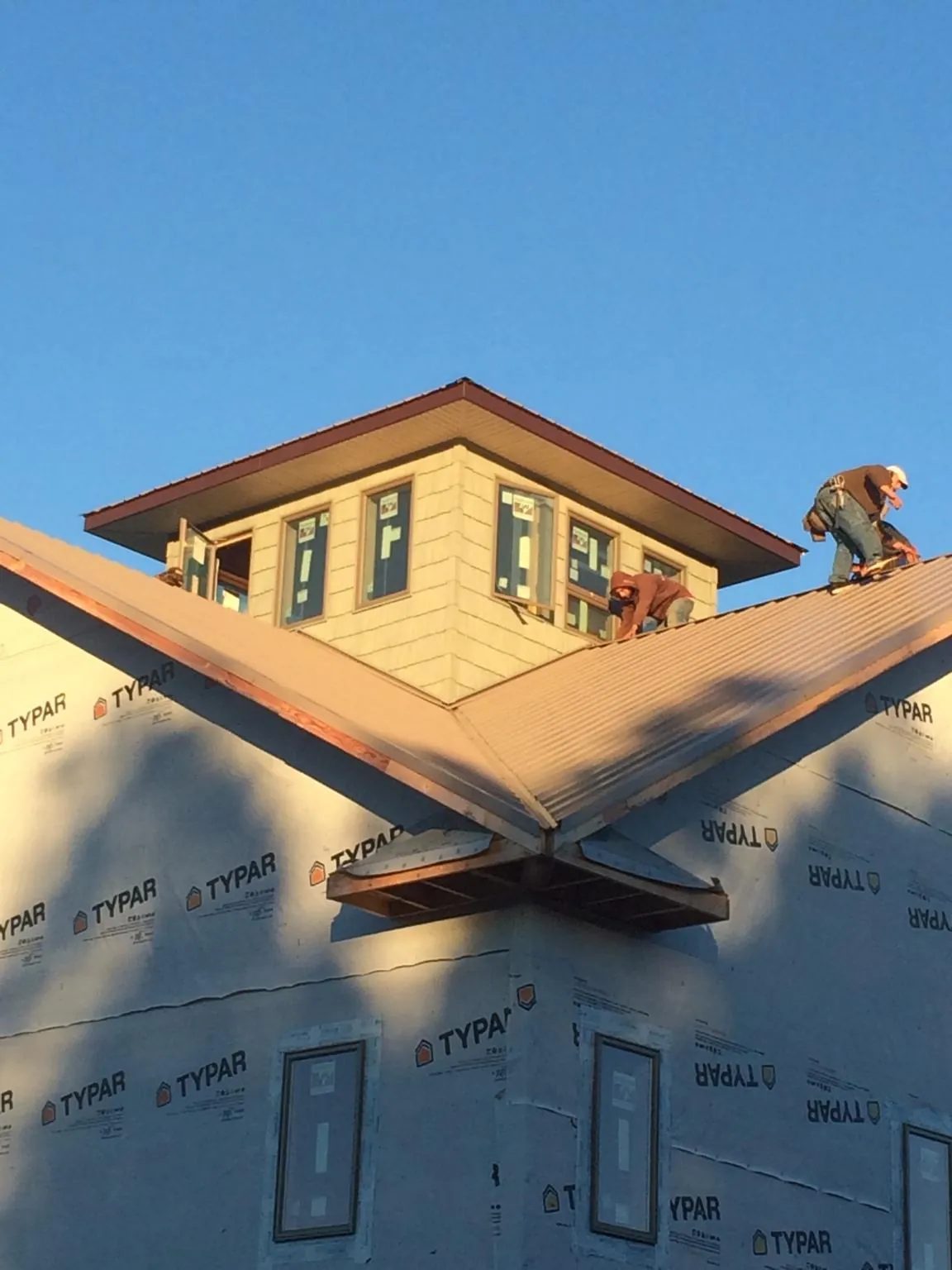 Roofers working around a rooftop cupola on a new metal roof at sunset — Roof Waterproofing in Chancellor by Roofing Brothers